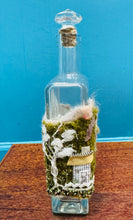 Load image into Gallery viewer, Gwaith ffelt a gwnio wedi ei wneud â llaw a’i lapio am botel wydr / Handmade felt and sewing work wrapped around a glass bottle