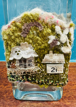 Load image into Gallery viewer, Gwaith ffelt a gwnio wedi ei wneud â llaw a’i lapio am botel wydr / Handmade felt and sewing work wrapped around a glass bottle
