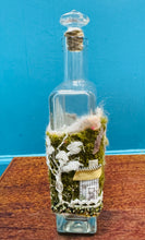 Load image into Gallery viewer, Gwaith ffelt a gwnio wedi ei wneud â llaw a’i lapio am botel wydr / Handmade felt and sewing work wrapped around a glass bottle
